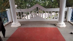 Ein überdachter Außenbereich mit rotem Teppich, weißer Balustrade und Säulen.