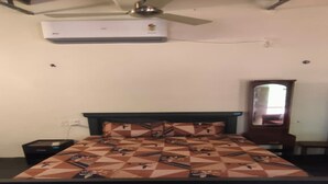 Ein Schlafzimmer mit Bett, Nachttisch, Kommode, Spiegel und Klimaanlage.
