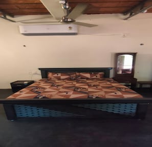 Quarto com cama, mesa de cabeceira, cômoda, espelho e ar condicionado.