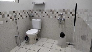 Ein Badezimmer mit Toilette, Dusche und Mülleimer.