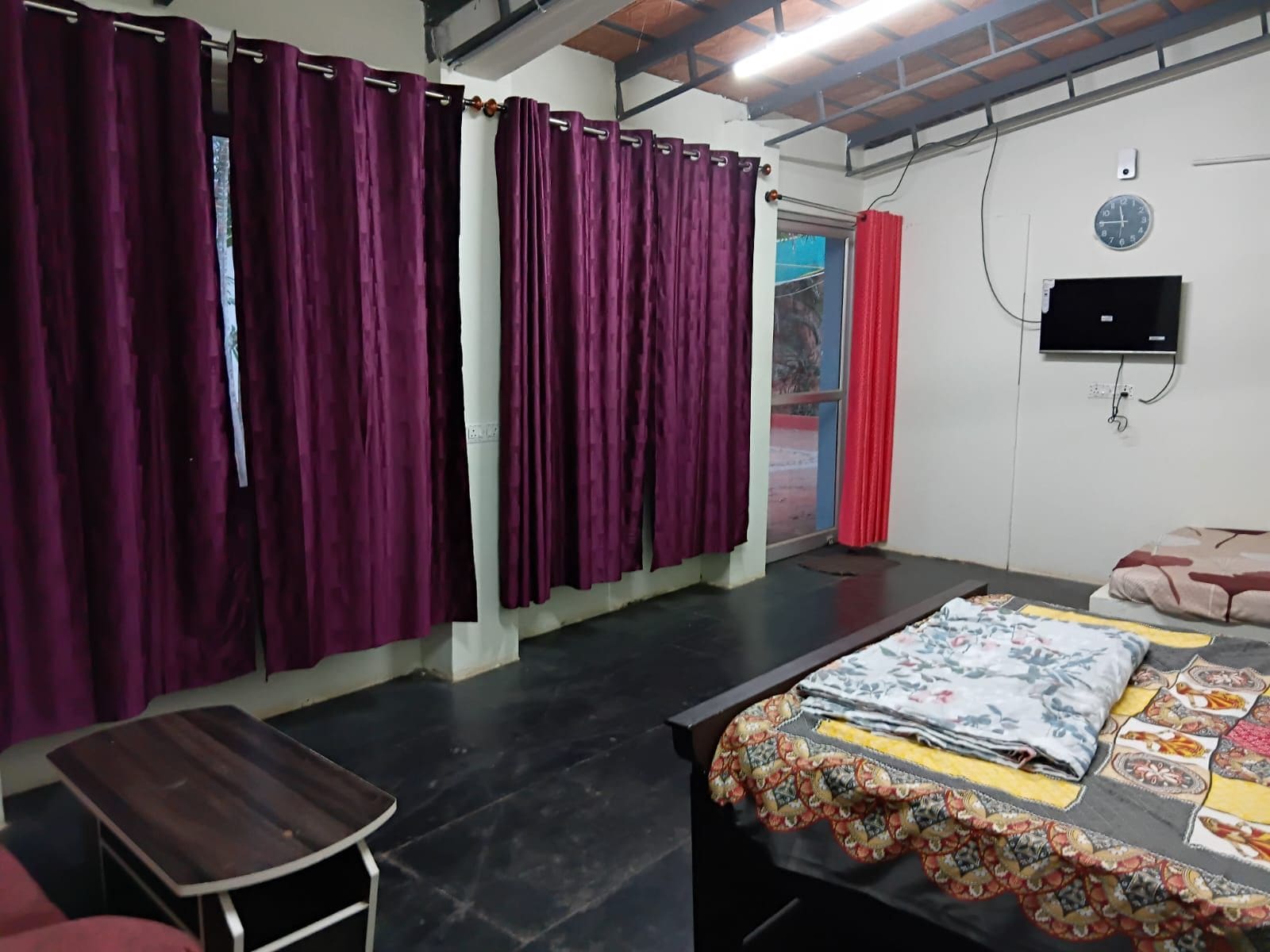 A room with a bed, a small table, and purple curtains.