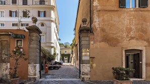Une rue étroite, bordée de bâtiments des deux côtés, avec un chemin pavé et une moto garée.