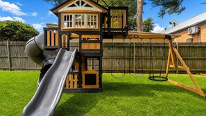 A playground with a slide, swings, and a playhouse.