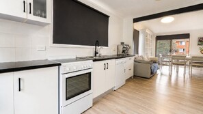 A modern kitchen with white cabinets, a black countertop, and a built-in oven.