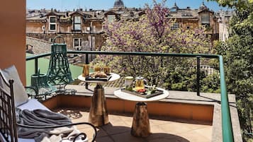Un balcón con una mesa para dos, una silla y vistas de la ciudad.