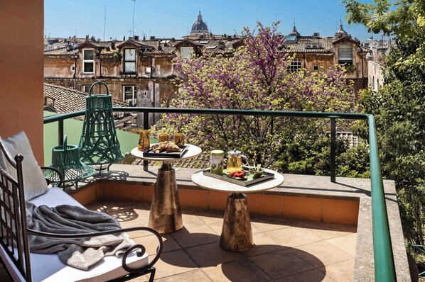 A balcony with a table set for two, a chair, and a view of the cityscape.