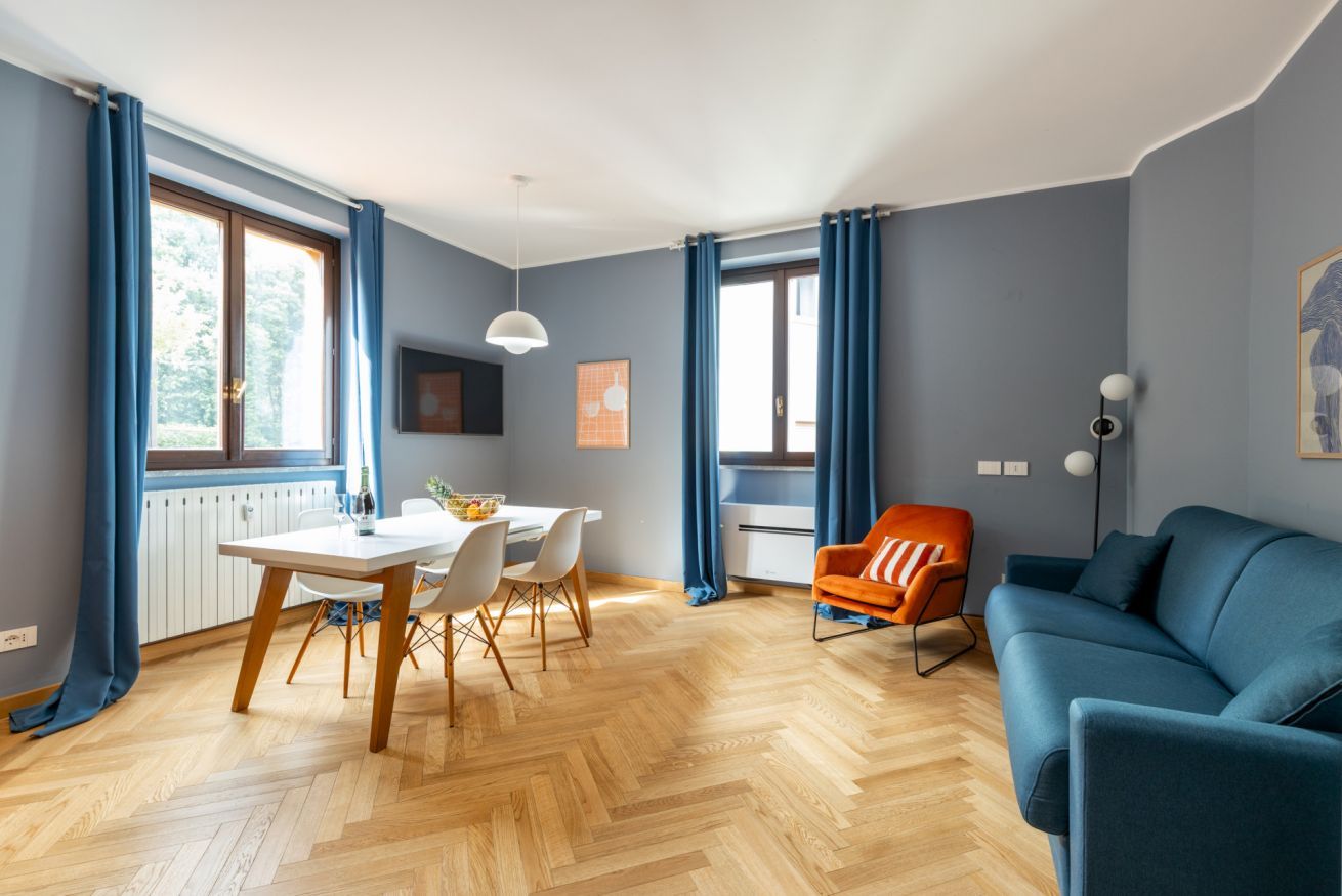A modern living room with a dining area, a sofa, and a chair.
