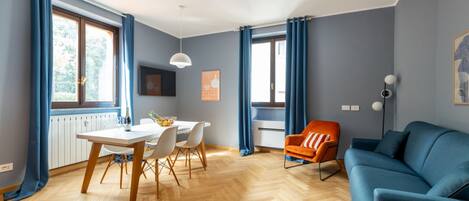 A modern living room with a dining area, a sofa, and a chair.