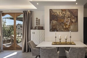 A dining area with a table, chairs, a chandelier, and a large abstract painting on the wall.