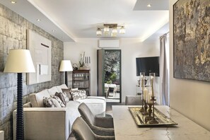 A modern living room with a sofa, a dining table with candles, and a view through a glass door to an outdoor area. - Villa in Rome with 3 bedrooms sleeps 8 (Rome)