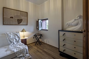 Una stanza con un letto, una lampada, una cassettiera, una finestra e un'opera d'arte appesa al muro.