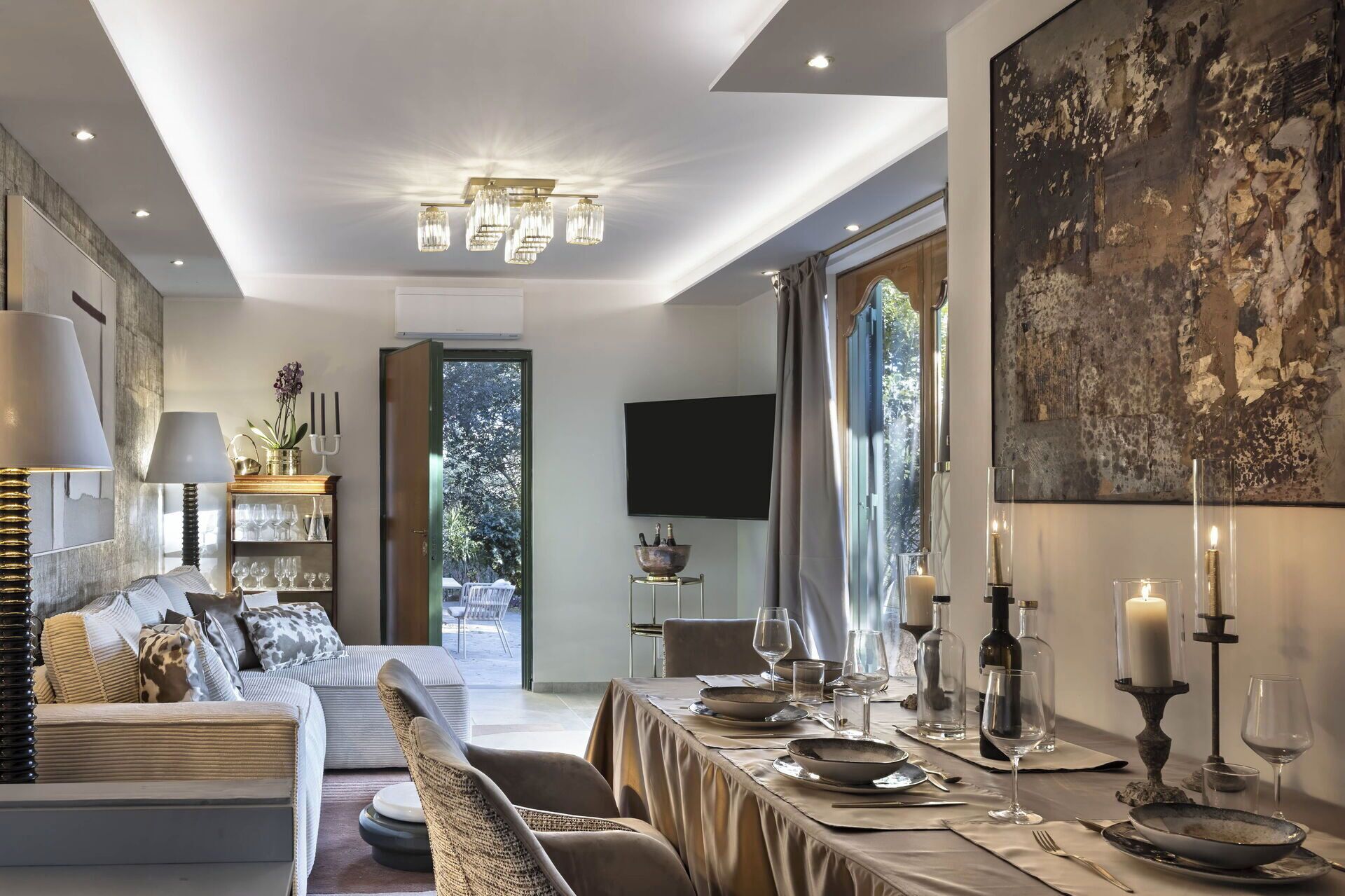 Una sala de estar moderna con sofá, mesa de comedor dispuesta para una comida y un gran ventanal con vistas.