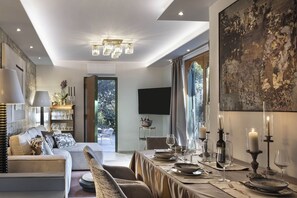 A modern living room with a sofa, dining table set for a meal, and a large window with a view.