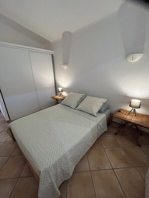Ein Schlafzimmer mit einem Bett, einem Nachttisch, einer Lampe und einem Kleiderschrank.