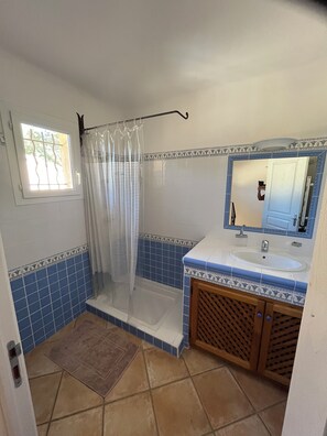 Ein Badezimmer mit Dusche, Waschbecken, Spiegel und blauen Fliesen.