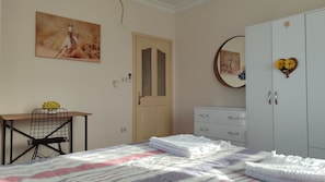 A bedroom with a bed, a desk, a wardrobe, and a painting on the wall. - Beautiful Comfy House in Fethiye (Fethiye)