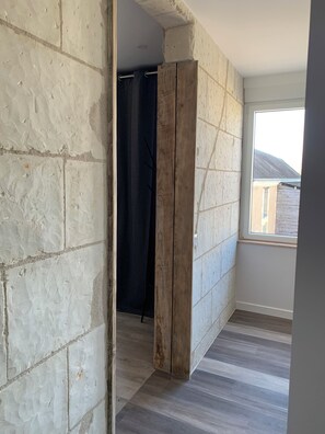 Ein Zimmer mit freiliegenden Ziegelwänden, einer Holztür und Blick auf ein Gebäude.