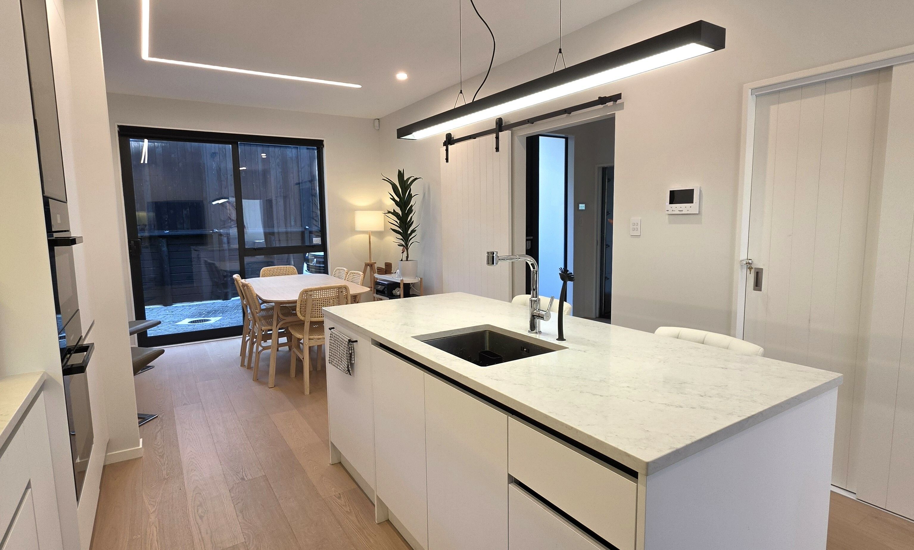 Een moderne keuken met een groot eiland, witte kasten en een geïntegreerde vaatwasser.
