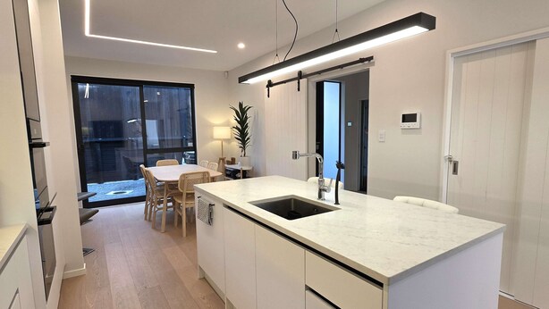 Una cocina moderna con una isla grande, muebles blancos y un lavavajillas integrado.