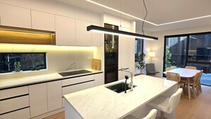 Una cocina moderna con una isla central, electrodomésticos integrados y una zona de comedor con mesa y sillas.