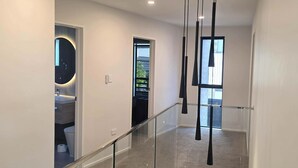 Un interior moderno con barandilla de vidrio, un espejo redondo y vistas al exterior.