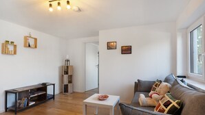 Una sala de estar con sofá, mesa de centro, estantería y ventana con vistas.