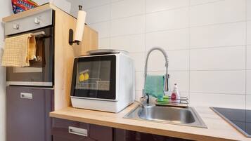 Een koffiezetapparaat/waterkoker, een koelkast, een oven, een kookplaat