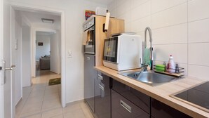 Una cocina compacta con microondas incorporado, un lavamanos con grifo moderno y una pequeña encimera.