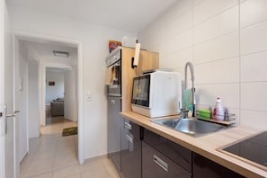 A compact kitchen with a built-in microwave, a sink with a modern faucet, and a small countertop.