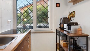 Una cocina compacta con un amplio ventanal, horno empotrado y cafetera.