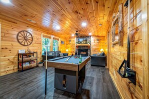 A wooden interior with a pool table, two sofas, a fireplace, and a wheel. - Cozy Mountain Cabin Retreat with Hot Tub, Fire Pit, and Game Room for Relaxing Getaways in Sevierville, Tennessee (Sevierville)