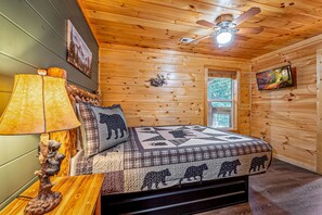 A wooden cabin bedroom with a bed, a ceiling fan, a window, and a television. - Cozy Mountain Cabin Retreat with Hot Tub, Fire Pit, and Game Room for Relaxing Getaways in Sevierville, Tennessee (Sevierville)
