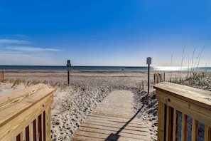A wooden boardwalk leading to a beach with a clear sky.