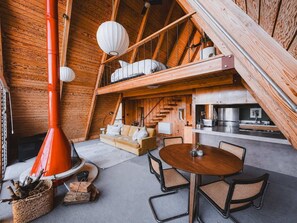 A loft-style room with a wooden interior, a fireplace, a sofa, a dining table, and a kitchen area. - Summit Haus Sunset Views & Outdoor Soaking Tub (Idyllwild-Pine Cove)