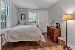 A bedroom with a large bed, a dresser, a lamp, and a window. - Cute Rustic Farmhouse Cottage Near the Coast in Southwest Harbor, Maine (Southwest Harbor)