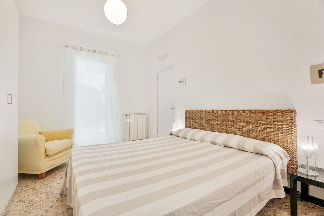 Een slaapkamer met een bed, een stoel, een radiator en een deur.
