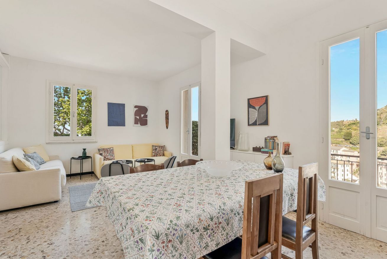 A spacious room with a bed, a sofa, a dining table, and chairs. There are windows with views of the outside.