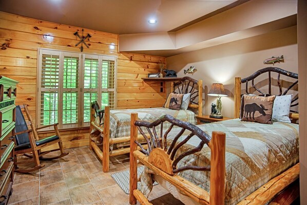 Un dormitorio de estilo rústico con dos camas de madera, una mecedora y un aparador.