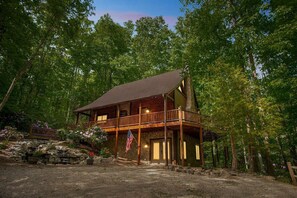 A cabin with a porch, a flag, and a stone wall.