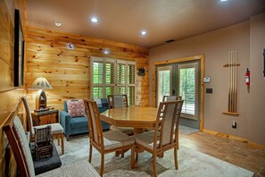Un interior de cabaña acogedor con una mesa de comedor de madera, sillas, un sofá y una chimenea.
