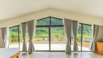 Una habitación con ventanas amplias, un balcón y vistas a un paisaje verde.