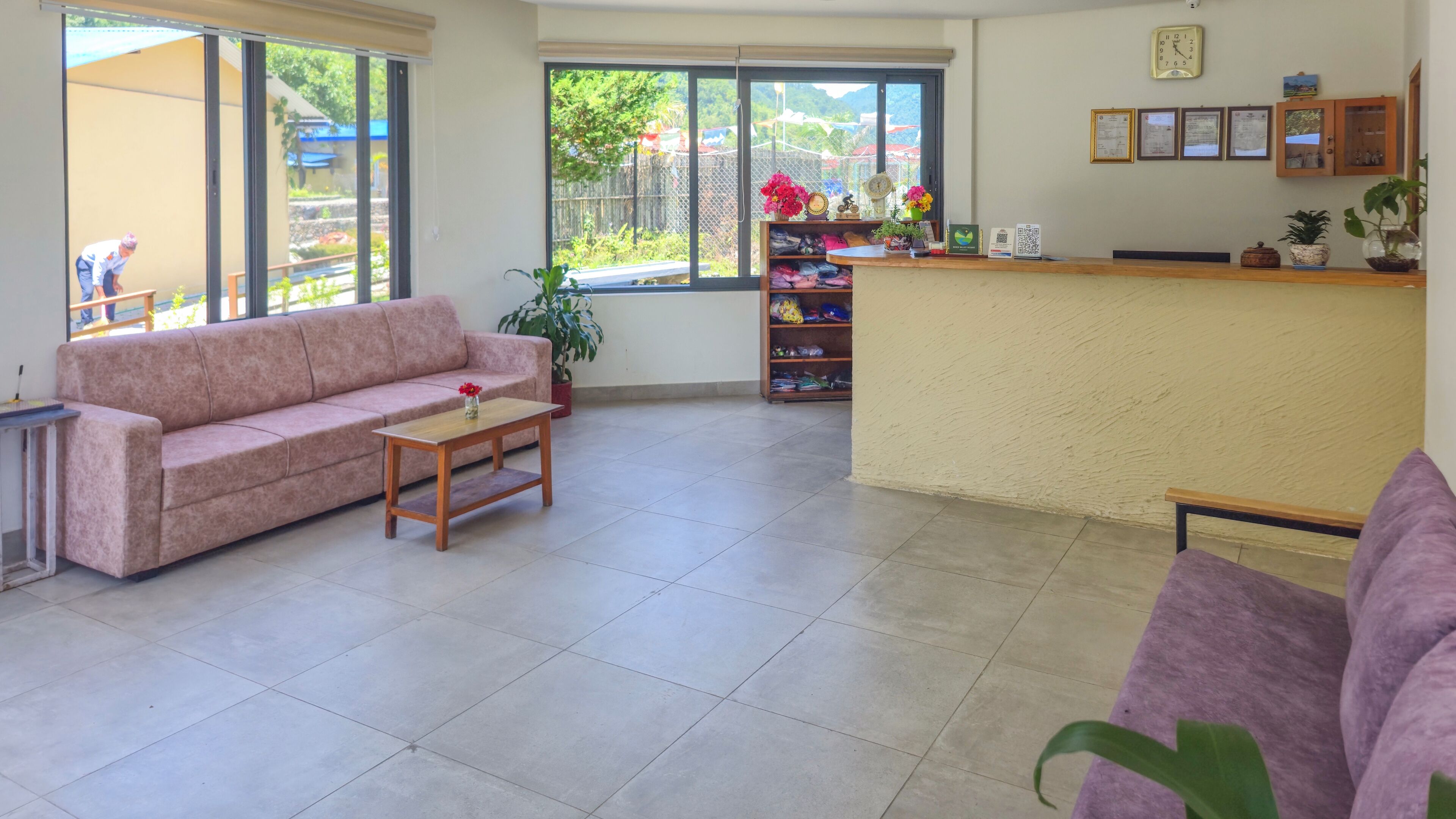 Una habitación con sofá, una mesita, un mostrador de recepción y vistas amplias por las ventanas.