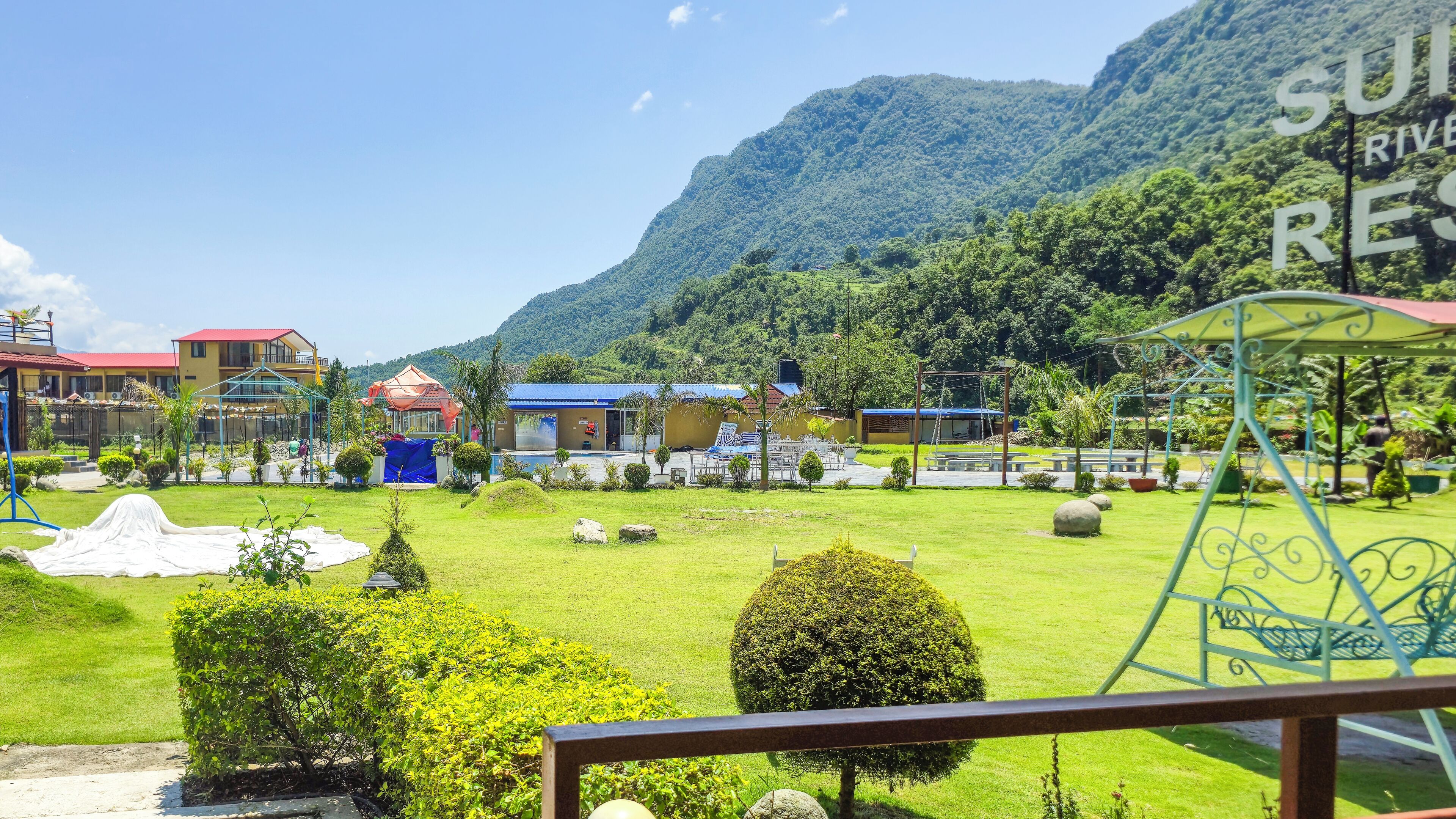 A resort with a swimming pool, a covered seating area, and a view of a mountain.