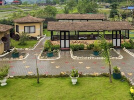 Un hotel con estructuras de techo de paja, un patio empedrado y plantas en macetas.