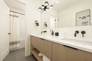 Un baño moderno con lavamanos doble, tocador y un espejo grande.