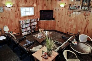 Een kamer met houten lambrisering, een bank, een salontafel, een boekenkast en een televisie.