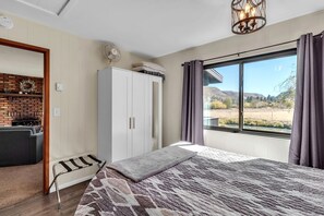 A bedroom with a bed, a wardrobe, a fan, a window with a view of the outdoors, and a chandelier.