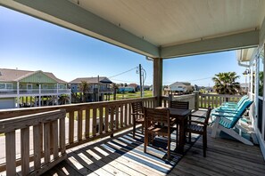 A wooden deck with a table and chairs, a railing, and a view of houses in the background.