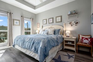 A bedroom with a bed, nightstands, a chair, and a window with curtains.