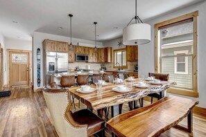 Une cuisine spacieuse dotée de meubles en bois, d’un grand îlot central et d’un coin repas avec une table en bois et des chaises en cuir.